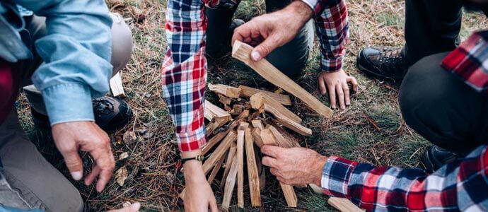 Photo of three generations males making campfire in forest